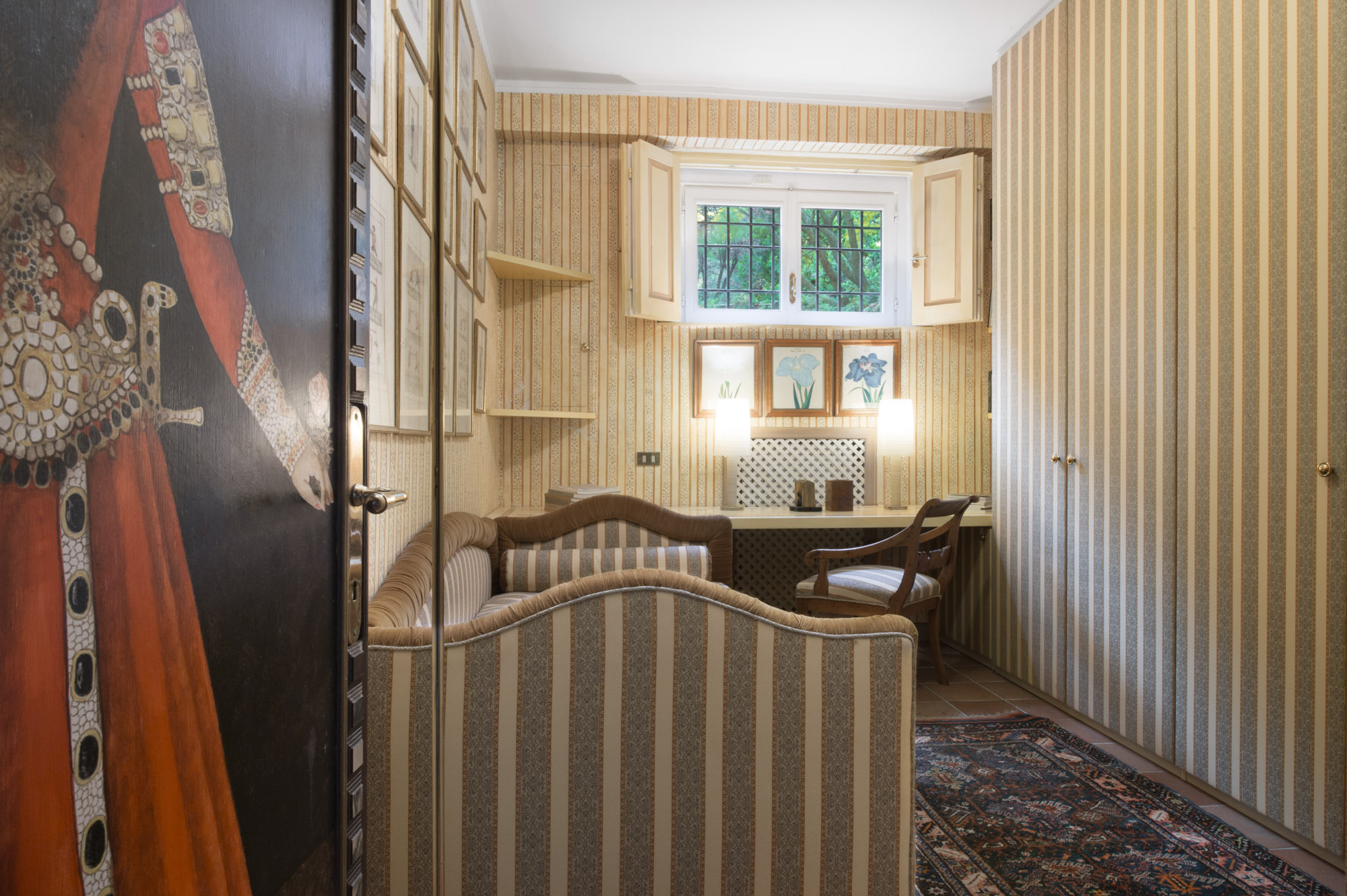 Single bedroom with striped walls and writing desk, lower floor of the main villa